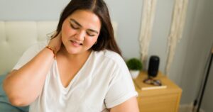 10 Early Morning Health Symptoms That Could Indicate Something Serious Woman suffering from neck pain early morning, feeling discomfort and muscle tension after a bad night's sleep