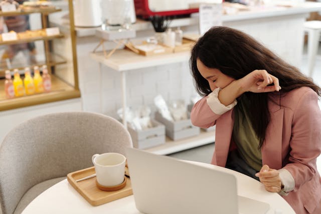 woman sitting at table, coughing