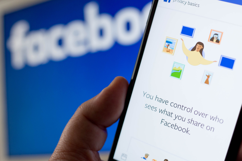 In a photo illustration, a screen from the Facebook app is seen on an iPhone in front of a Facebook logo, April 7, 2018.