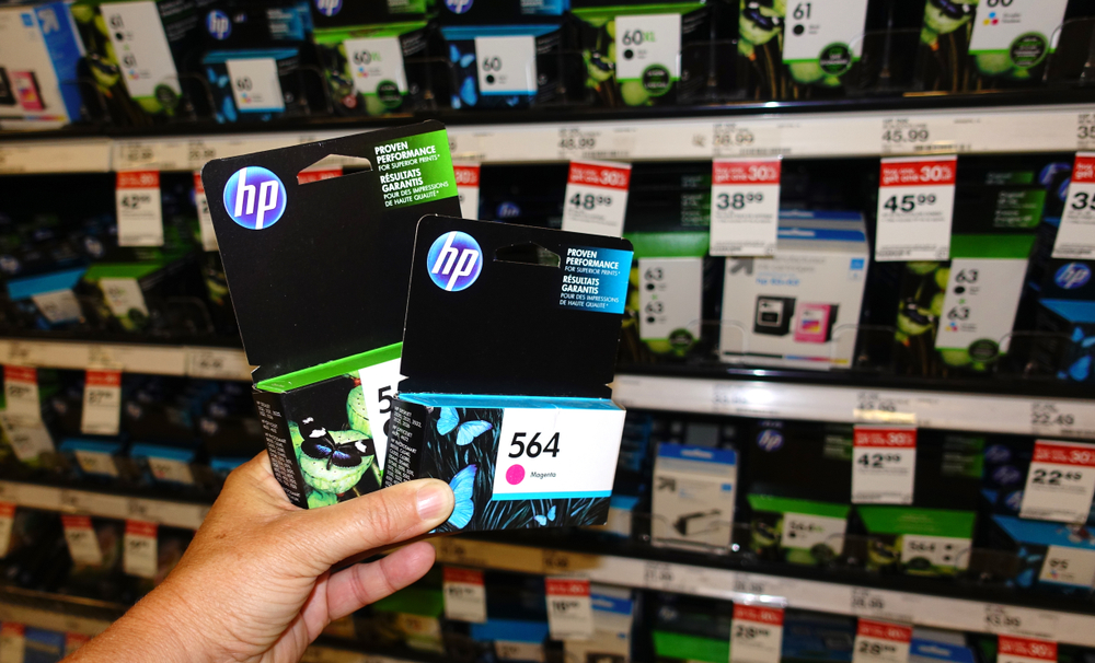Vista, CA / USA - July 21, 2018: A hand holing up two packages of HP printer ink in front of product display in a store