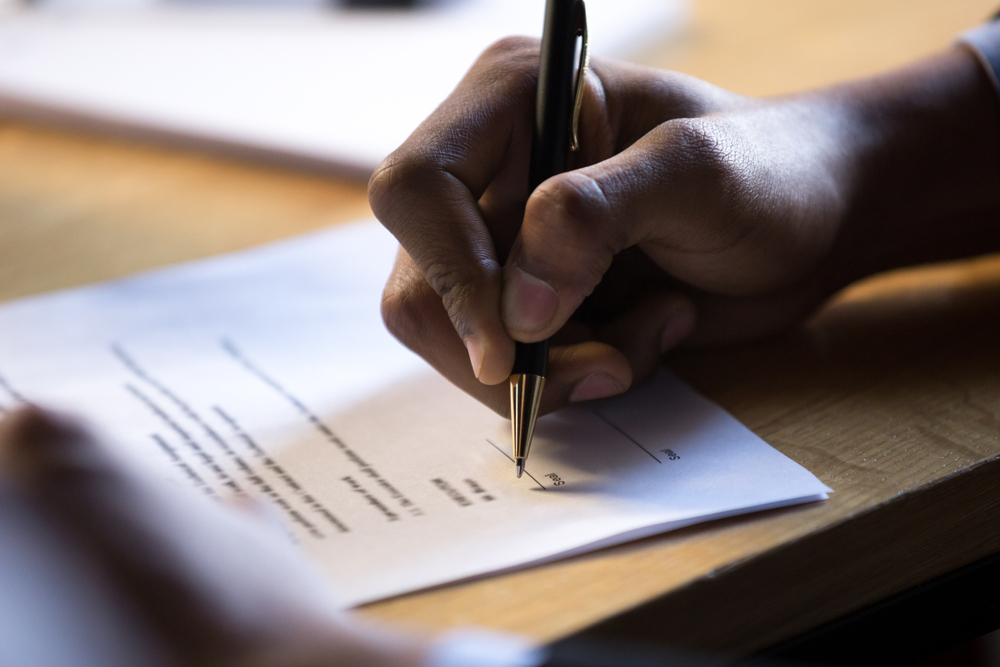 Male african hand signing financial contract concept, black businessman put write signature on legal corporate paper fill document form buy insurance loan, making business agreement, close up view