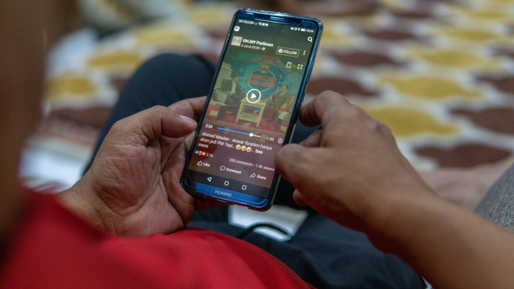 Selangor, Malaysia - July 9, 2019: Watching videos in Facebook apps by using a Huawei smartphone on the hands.