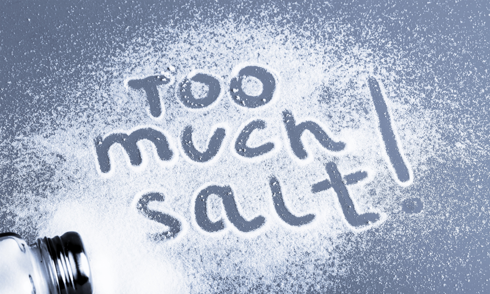 Scattered salt on the table with the words Too much salt!
