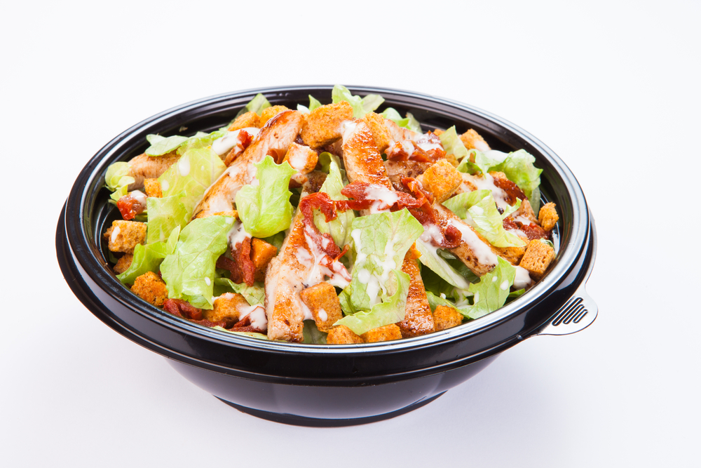 Close up of take away bowl with fast food salad with grilled chicken
