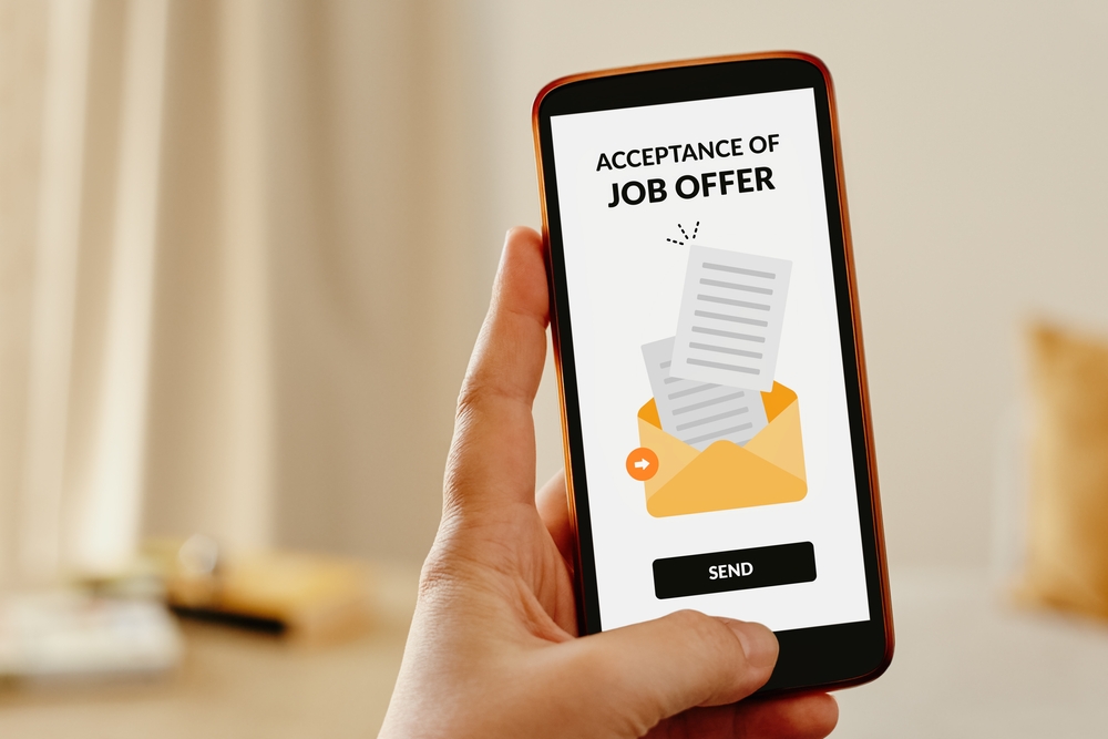 Female hand sending an email from mobile phone to accept a job offer.