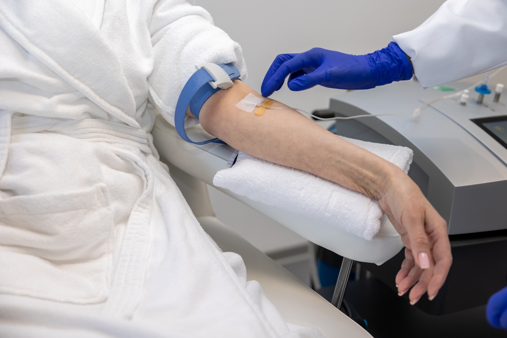 Woman receiving intravenous vitamin therapy in wellness center or beauty salon sitting in armchair.