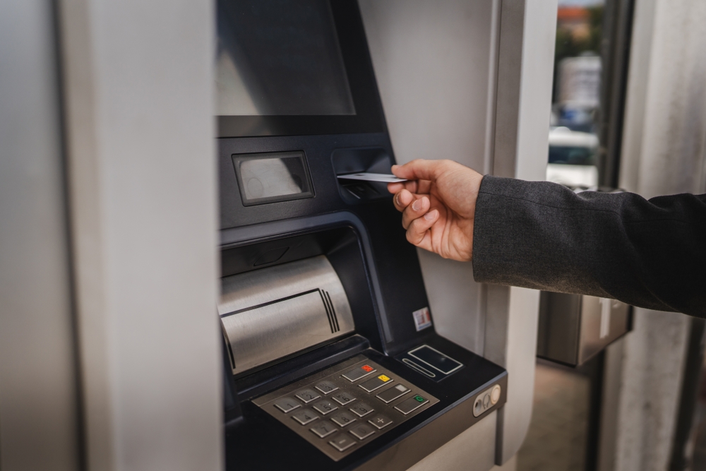 Close up of adult caucasian man hand hold credit card use cash machine on street
