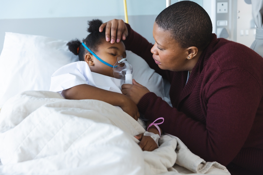 African american girl patient lying on bed with oxygen mask, with her mother at hospital. Hospital, motherhood, family, medicine and healthcare, unaltered.