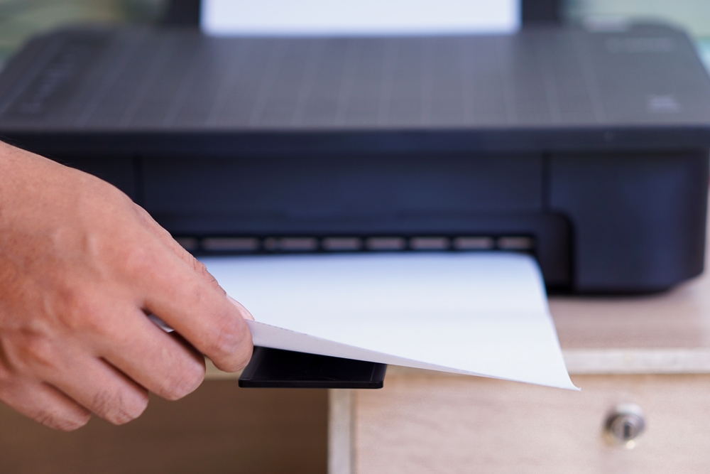 A person taking printed paper from a printer