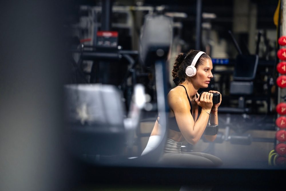 Fit and strong caucasian woman training with weights in gym.