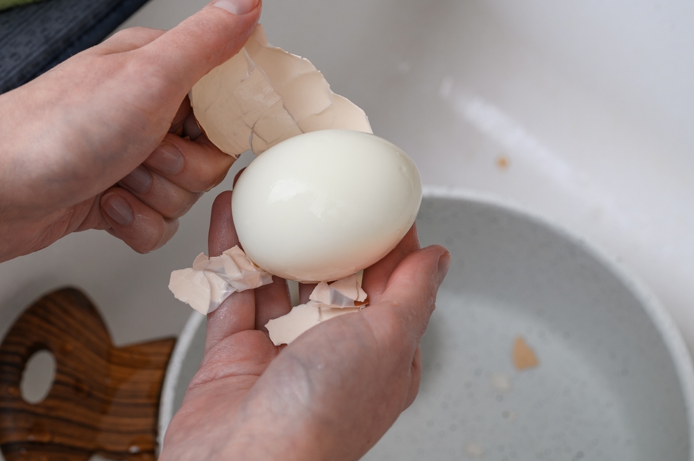 Hard-boiled egg being peeled close-up