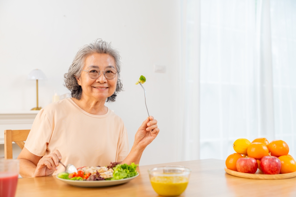 Portrait of Happy Asian senior woman having lunch or dinner at home. Elderly woman enjoy healthy lifestyle eating organic clean food vegetable and fruit. Retired people healthcare wellness self-care.