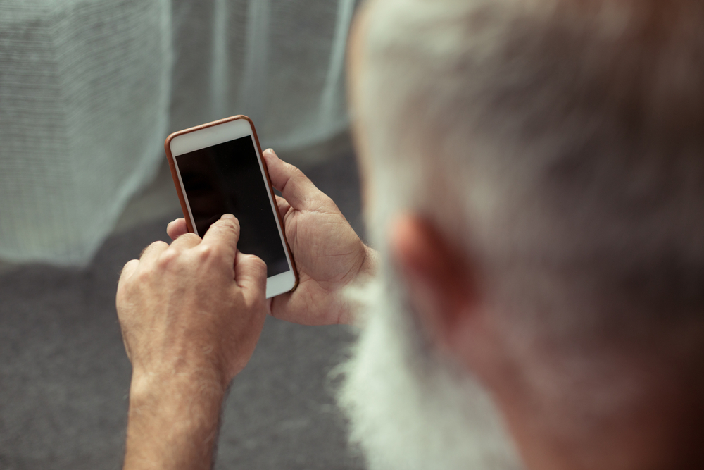 cropped view of senior man using smartphone and pointing on it