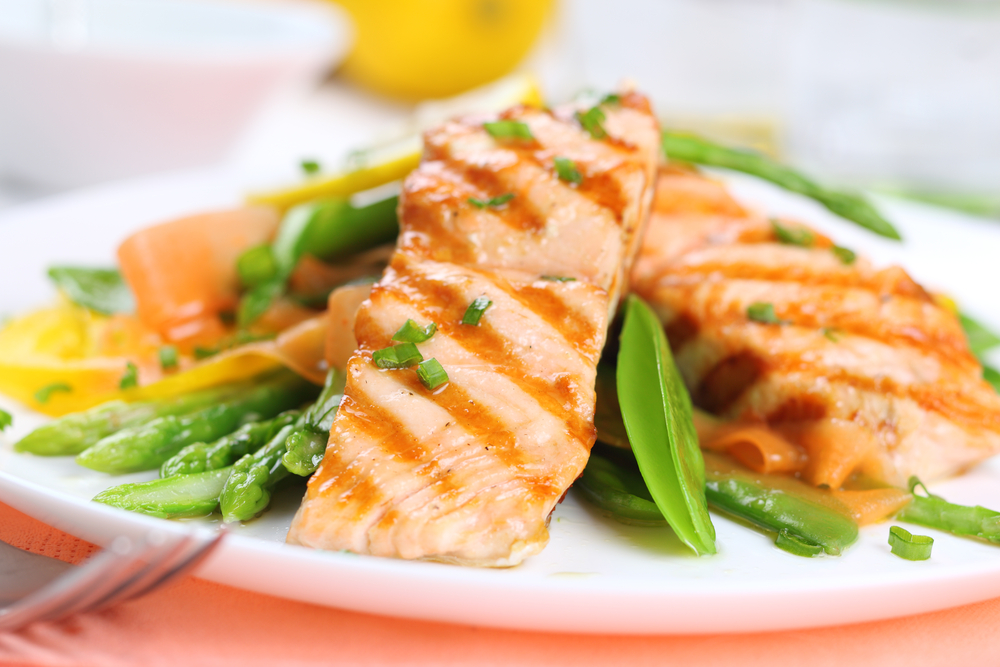 grilled salmon with spring vegetables on white plate, soft focus