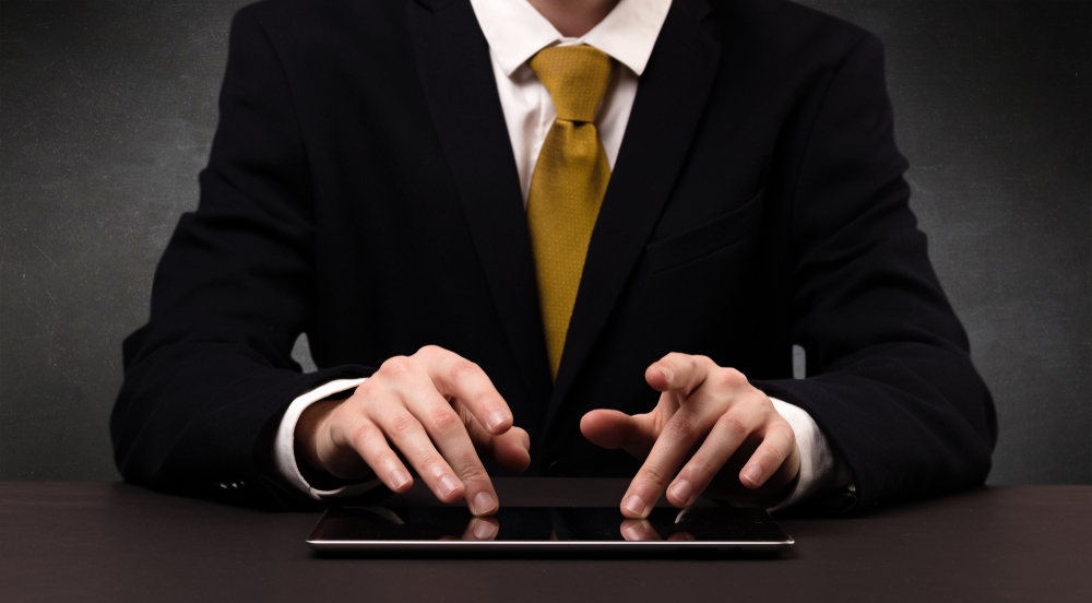 Businessman in suit typing with dark background