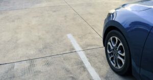 a dark colored car parked in a paved parking lot.