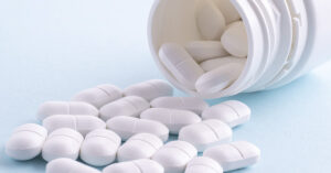 White pills spilling out of a bottle. Pharmaceutical drug concept