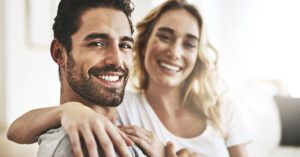 Couple smiling. Woman had arm around man's back and shoulders