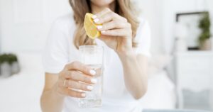 woman squeezing lemon juice into water. Lemon water concept