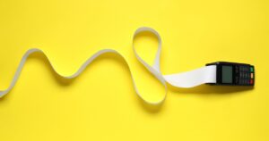 World-Leading Biomedical Scientist Sounds The Alarm: Don’t Touch Receipts Payment terminal with thermal paper for receipt on yellow background, top view