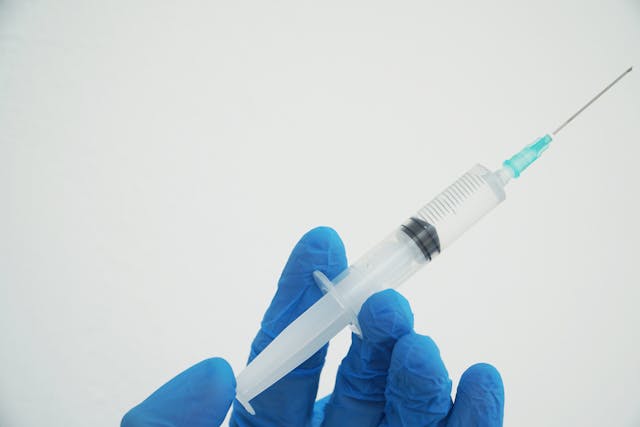 gloved hand holding syringe