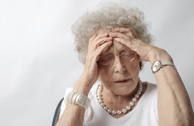 Elderly lady holding her head