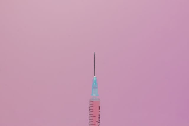 Syringe on pink background