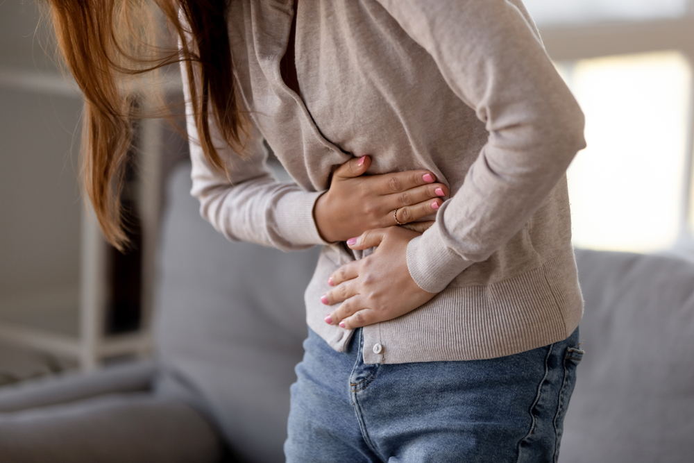 Close up woman holding belly, feeling discomfort, health problem concept, unhappy girl standing at home, suffering from stomachache, food poisoning, gastritis, abdominal pain, menstrual period