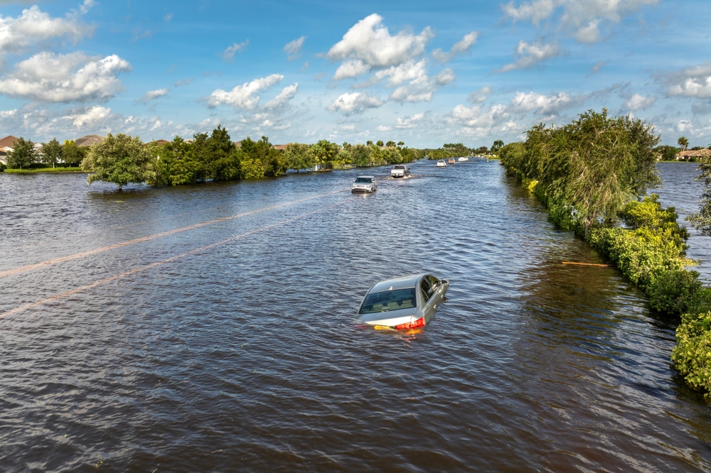 Hurricane rainfall flooded road. Drowned car on city street in Florida residential area. Consequences of hurricane natural disaster.