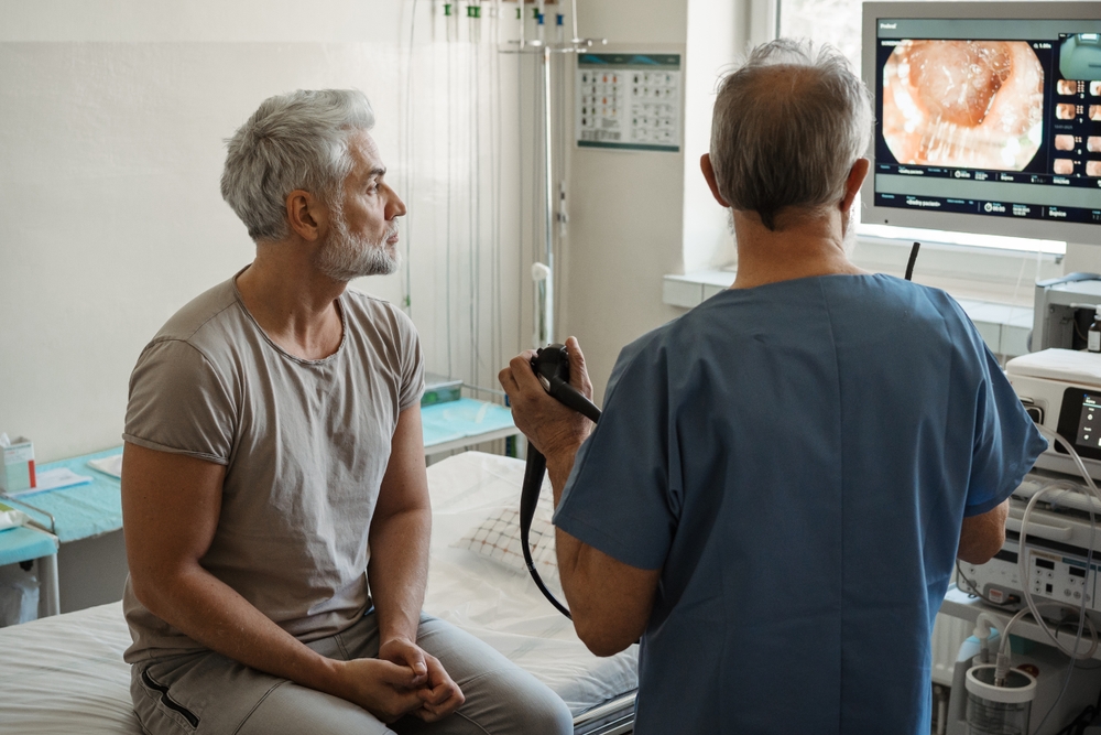 Doctor explaining colonoscopy results to patient using monitor images.