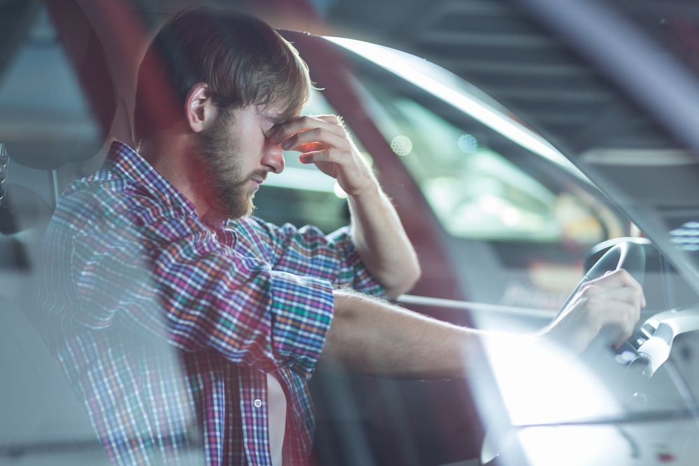 Image of worried driver sitting in his car at workshop