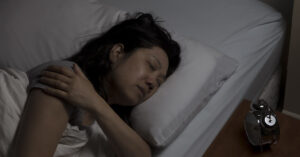 Woman sleeping at night experiencing nighttime shoulder pain