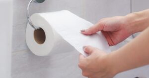 How Often Should You Go to the Toilet? 7 Gut Health Facts Close-up of in Hand using a toilet paper.