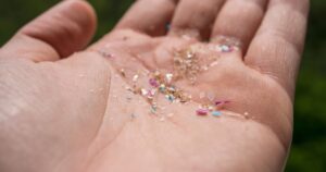 A person holding microplastics gathered from the ocean in his hand. The concept for plastic pollution and climate change.