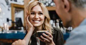 Interested excited falling in love mature woman listening to her husband man boyfriend while drinking coffee in restaurant cafe on a date