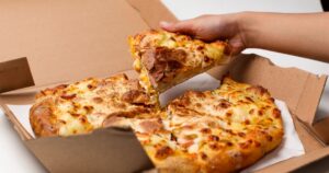 This 50-Year-Old Pizza Chain Just Filed for Bankruptcy — Here's What Happened hand takes pizza from box