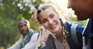Hiking, nature and people with conversation, travel and relax with weekend break, hobby and adventure. Group, outdoor and friends with discussion, journey and fitness with smile and calm in forest