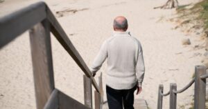 An elderly Spanish pensioner walks down the stairs to the beach
