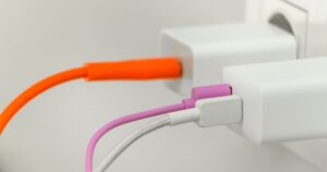 phone chargers and their cords plugged into the wall socket