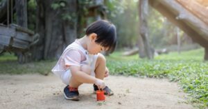 Pinworms In Children. What They Are And Why They Cause Nighttime Itching little boy playing in the sand with toy trucks and a shovel under dappled sunlight, enjoying a peaceful outdoor moment surrounded by trees and nature