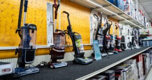 Row of upright vacuum cleaners on display in store aisle. Brampton, Canada - November 16, 2025.