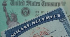 Your Social Security Check Could Jump in 2027 - Here's What the Numbers Show social security card in foreground emphasized with a blurred background of a united states treasury check
