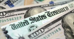 United States Treasury refund check or stimulus bill with many hundred dollars banknotes close up