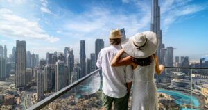 These 10 Countries Will Give You Residency (or a Passport) If You Buy Property A hugging tourist couple enjoys the panoramic view of the skyline of Downtown Dubai, UAE