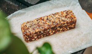 Close-up image of a nut and sesame seed protein bar on parchment paper, ideal for healthy snacking.