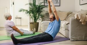 The Happiest (and Worst) States to Retire in the U.S. Right Now Elderly couple enjoying yoga exercise on mats at home, promoting healthy and positive aging.