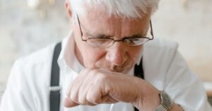 12 Old Age Habits Everyone Notices, But Nobody Talks About Elderly man with white hair and glasses deep in thought indoors.