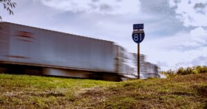 Blurred truck on Interstate 81 South with clear blue sky and grassy foreground.