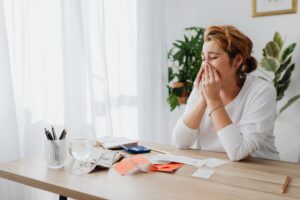 Social Security Could Cut Your Benefits by 22% — Here's the Timeline Woman looking stressed while managing finances at her office desk with papers and calculator.