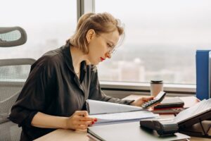 The $400,000 Widow Survivor Benefits Decision You Have 12 Months to Make Woman accountant calculating financial documents at office desk.